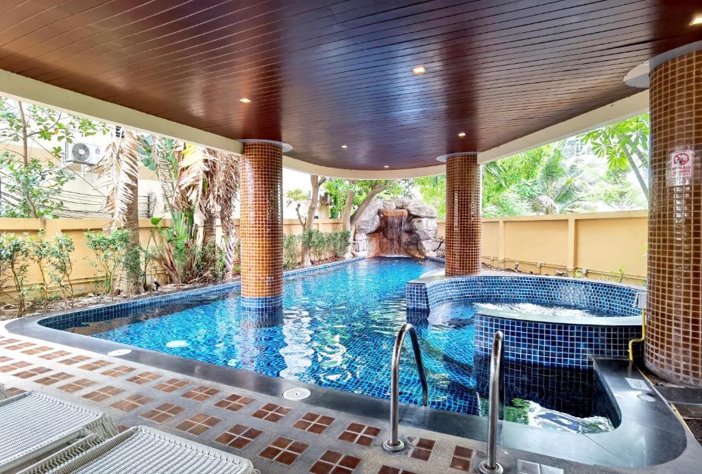 een groot zwembad met een waterval in een huis bij Nova Gold Hotel Pattaya in Pattaya