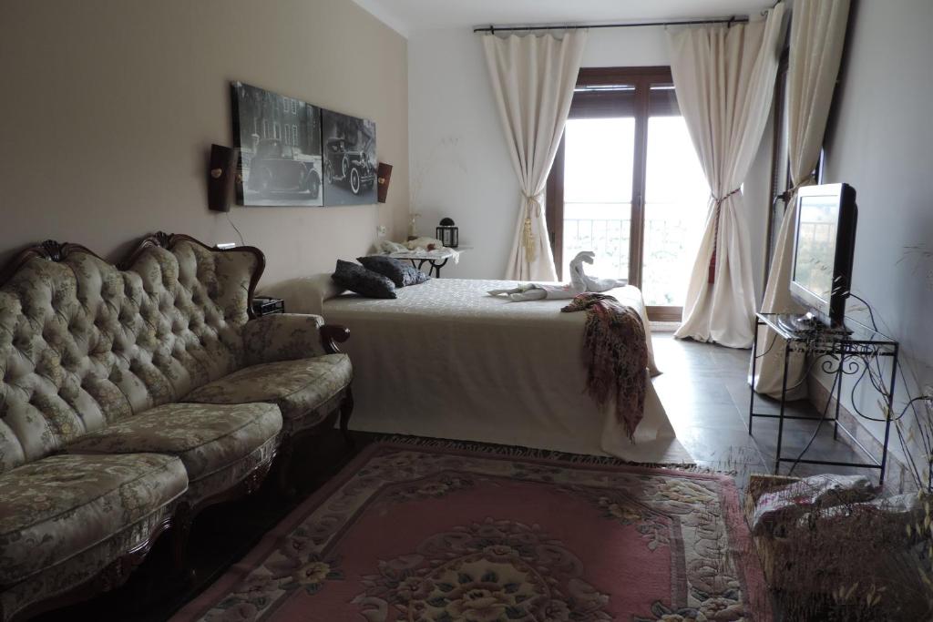 a bedroom with a bed and a couch and a window at Caseria 7 Fuentes in Hinojares