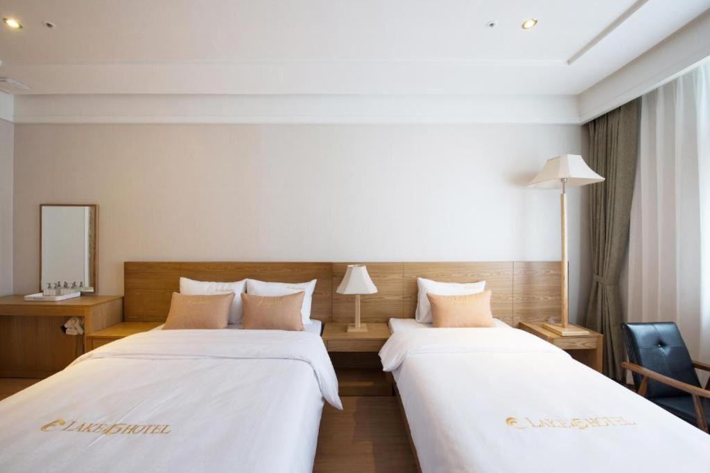 2 bedden in een hotelkamer met witte lakens bij Lake 45 Hotel in Naju