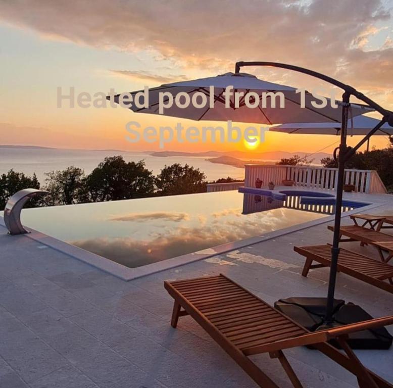 puesta de sol sobre una piscina con banco y sombrilla en Sea view Luxury Hotel Villa Conte with private swiming pool and romantic SPA, en Podstrana