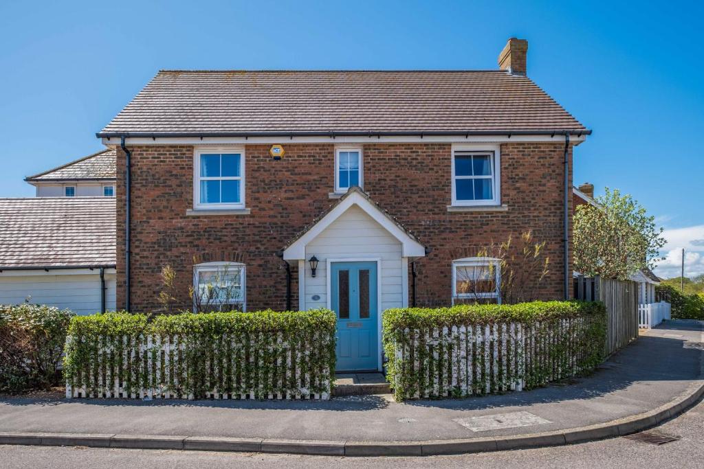 una casa de ladrillo con una puerta azul en una calle en Camber Cottage, en Camber