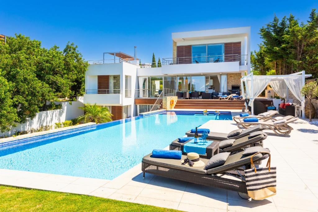 a villa with a swimming pool with lounge chairs and a house at Annabel Beach Palace in Lachi