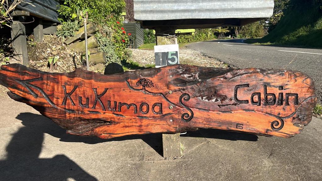 a wooden sign on the side of a road at Kukumoa Cabin in Opotiki