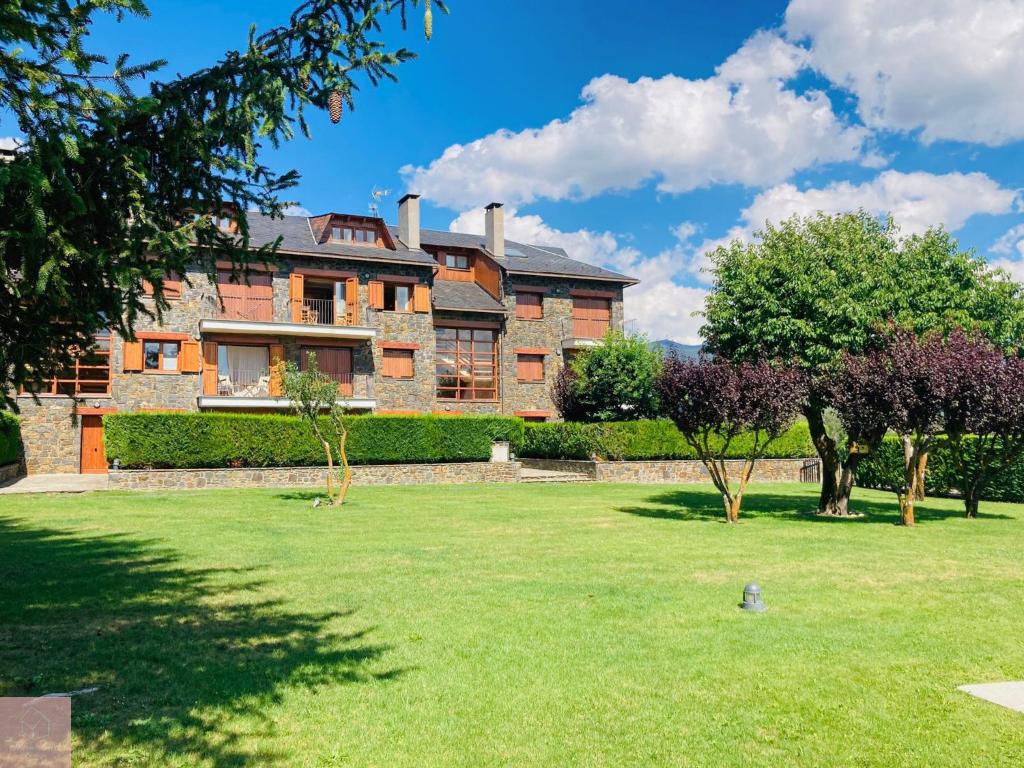 a large brick house with trees in the yard at Dúplex a Age amb piscina in Puigcerdà