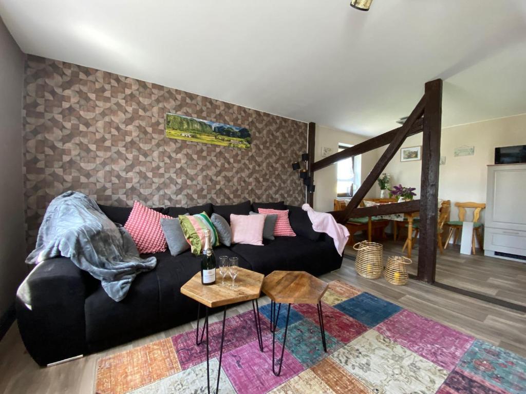 un salon avec un canapé noir et une table dans l'établissement Ferienwohnung-Familienidylle-im-Vogtland-80qm, à Neumark