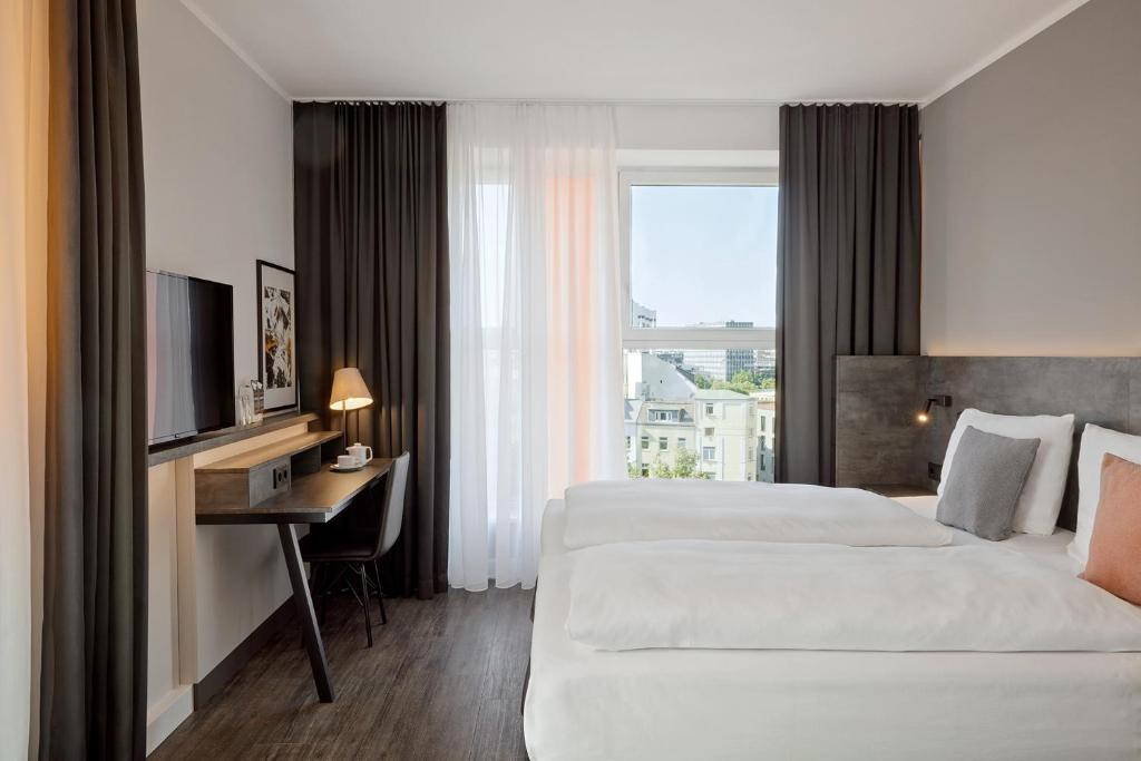 a hotel room with two beds and a desk and a television at THE SCOTTY Hotel Hamburg in Hamburg