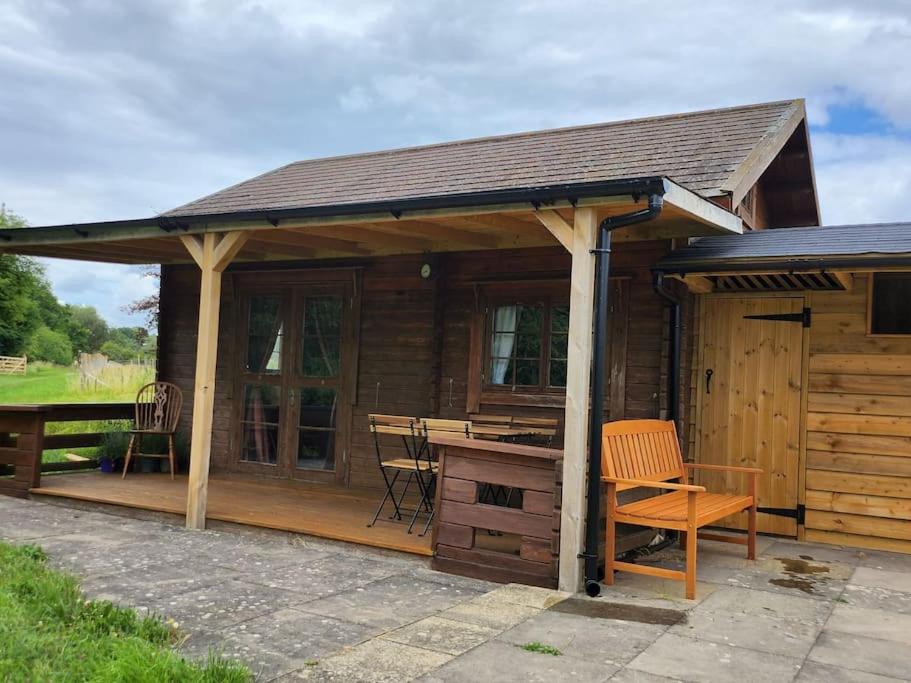 um chalé de madeira com uma mesa e uma secretária em The Meadow em Lapworth