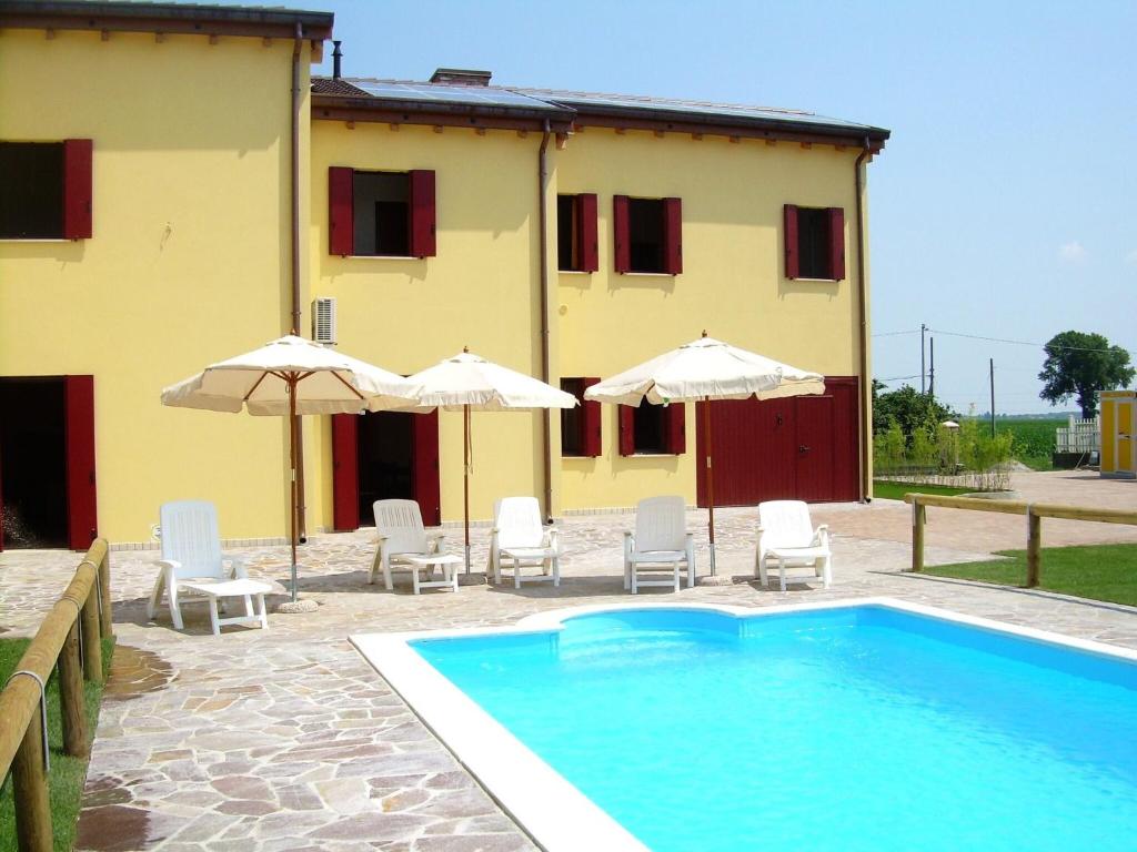 uma casa com piscina, cadeiras e guarda-sóis em Cozy Holiday Home in Ariano nel Polesine with Swimming Pool em Il Piano