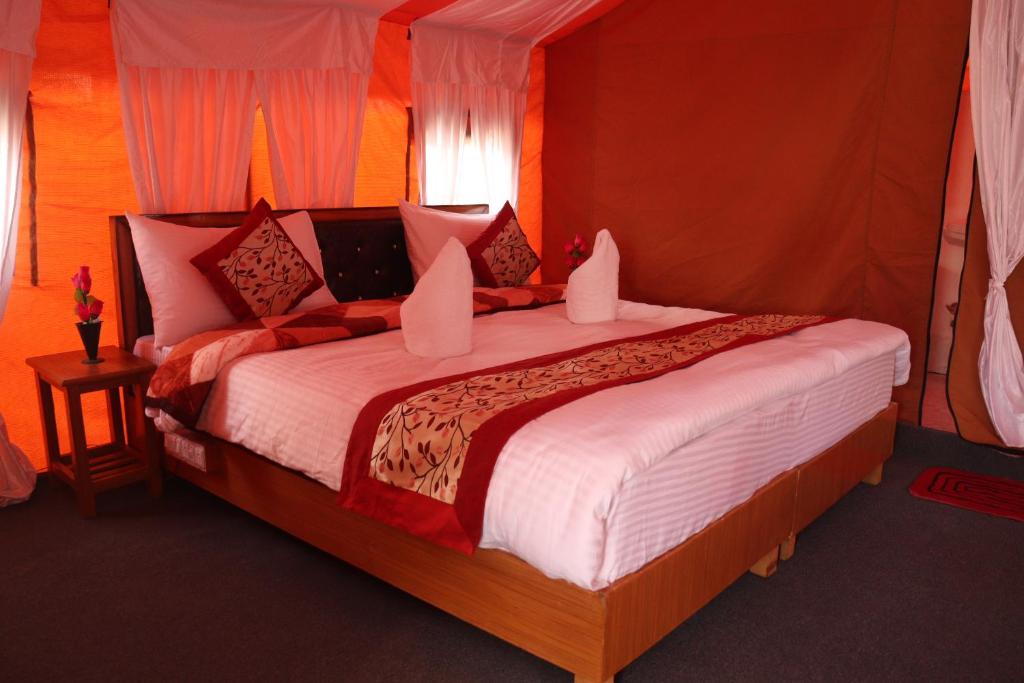 a bedroom with a large bed with red walls at Ldazes Camp in Hundar