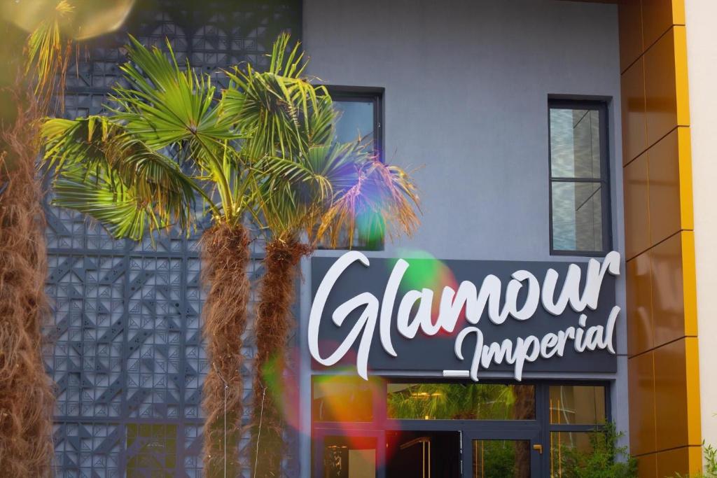 two palm trees in front of a building with a sign at HOTEL GLAMOUR IMPERIAL in Buzau