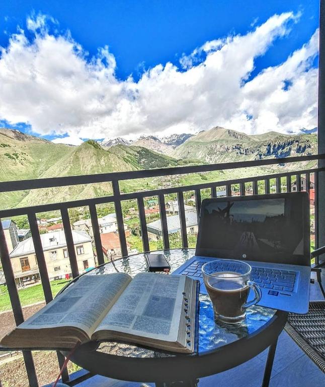 Una mesa con un libro y una computadora portátil y una taza de café. en Kazbegi 4U, en Kazbegi