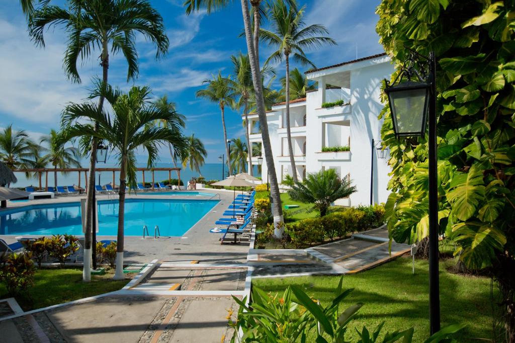 a view of a resort with a swimming pool and palm trees at Vista Vallarta All Suites On The Beach in Bucerías