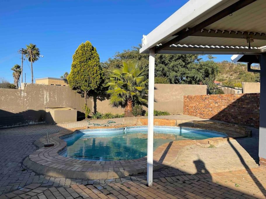 uma pequena piscina num pátio com um guarda-sol em Home in Suideoord, Jhb south em Joanesburgo