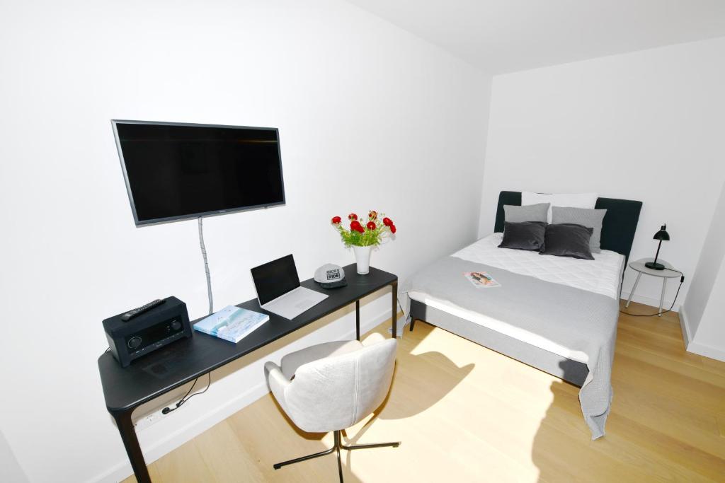 um quarto com uma secretária e uma cama com uma televisão em Glück Auf Appartements Hillerstraße Köln em Colónia