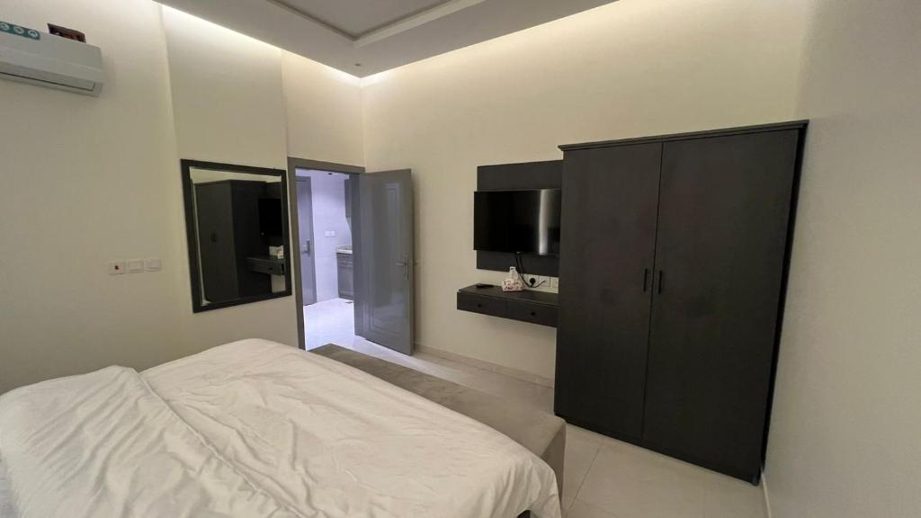 1 dormitorio con 1 cama y armario negro en شقق ميسم الورد للشقق المفروشه en Mahlal