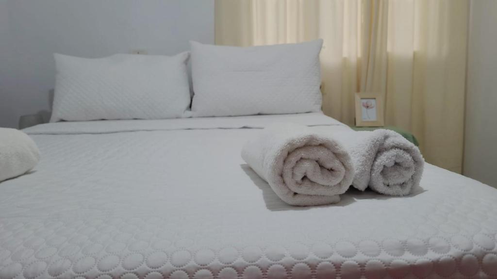 un lit blanc avec des serviettes dessus dans l'établissement KORETA APARTMENT, à Vlorë