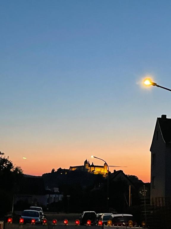 een zonsondergang met auto's in een straat met een straatlicht bij Peaceful holiday in Würzburg
