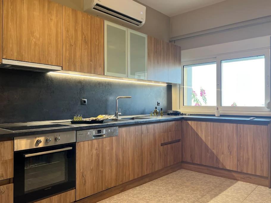 a kitchen with wooden cabinets and a sink and a window at Elaia Apartment in Kavala