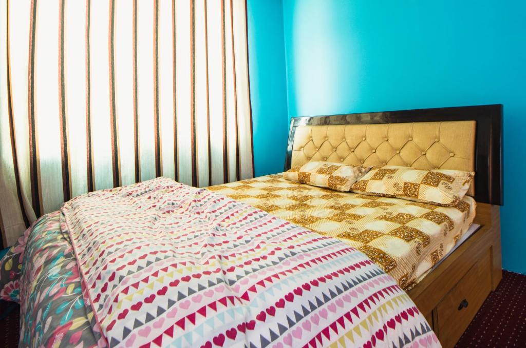 a bed in a bedroom with a blue wall at Season homestay in Kathmandu