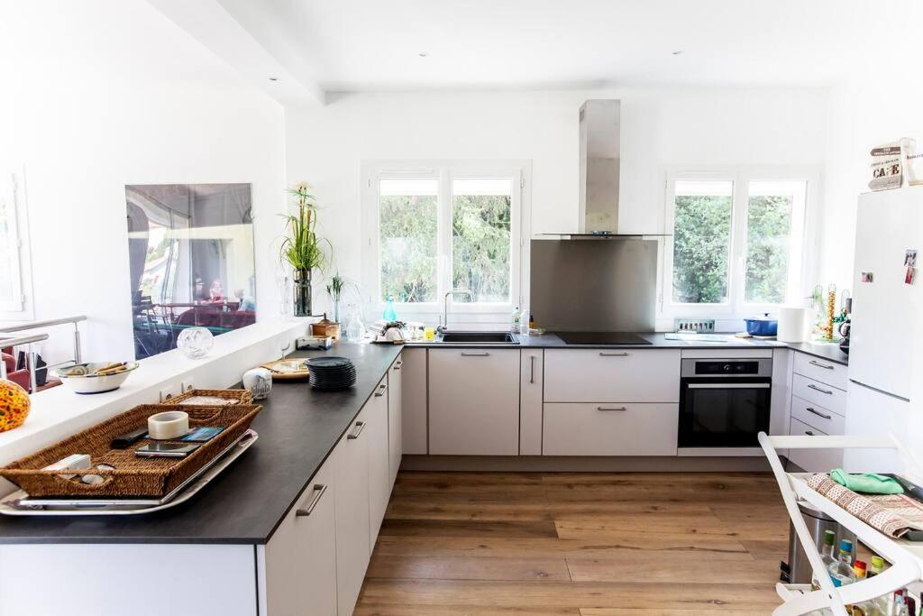 une cuisine avec des armoires blanches et un comptoir noir dans l'établissement Havre de paix familial avec grand jardin, à Marseille