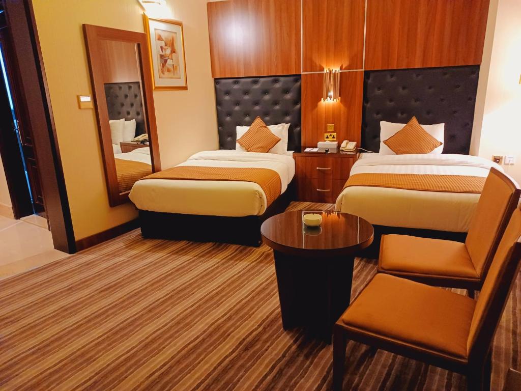 Royal Qatar Hotel في الدوحة: غرفة فندقية بسريرين وكرسي