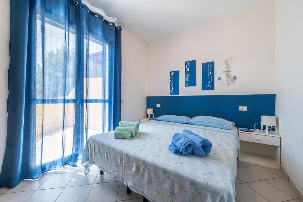 sypialnia z niebieskim łóżkiem i dużym oknem w obiekcie Casa Vacanza Casi 2 w mieście Villasimius