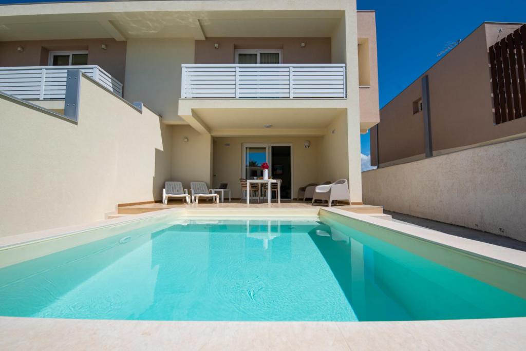 una casa con piscina frente a una casa en Charming House Sveleo - SiciliaVacanza en Marzamemi