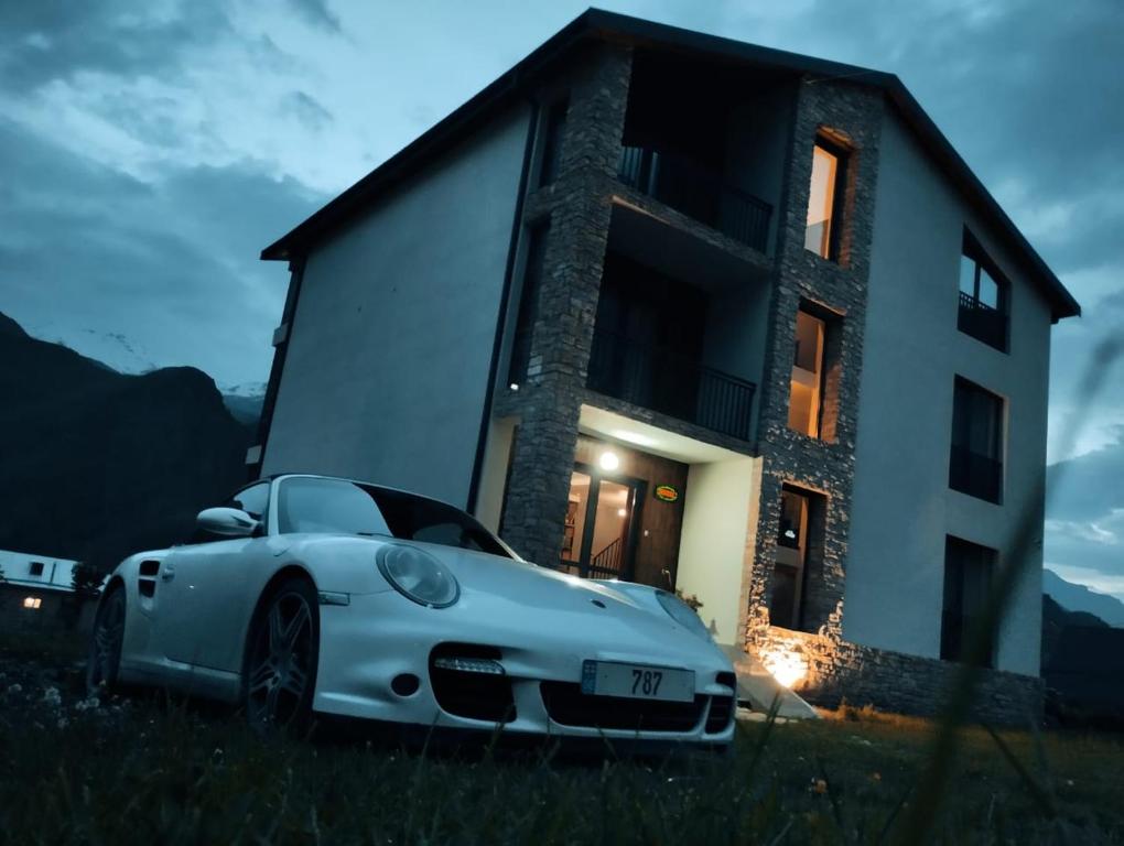 a white car parked in front of a house at Kazbegi 4U in Stepantsminda