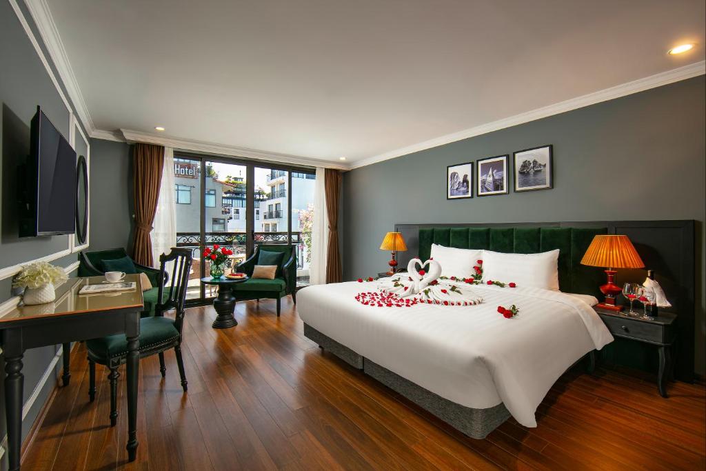a bedroom with a large bed and a desk and a room at La Selva Premium Hotel in Hanoi
