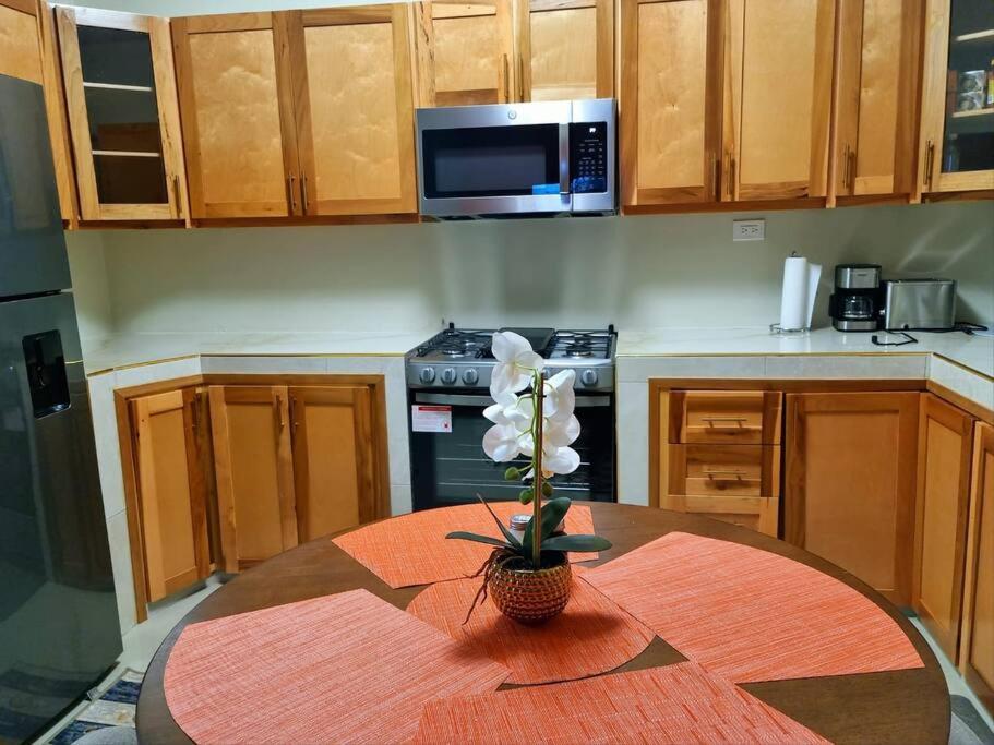 a kitchen with a table with a vase of flowers on it at S.G Apartment Complex. in Linstead