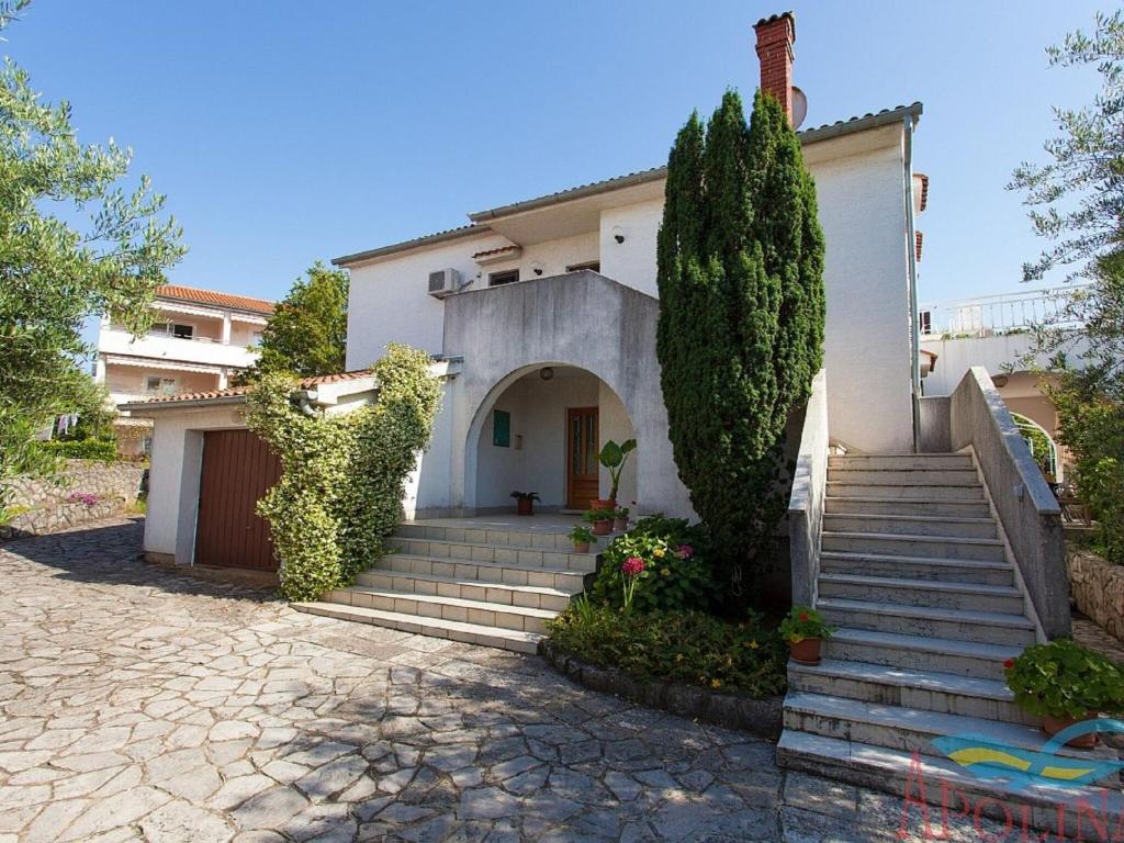 een wit huis met een trap naar een deur bij Nice apartment with terrace and grill for use in Malinska