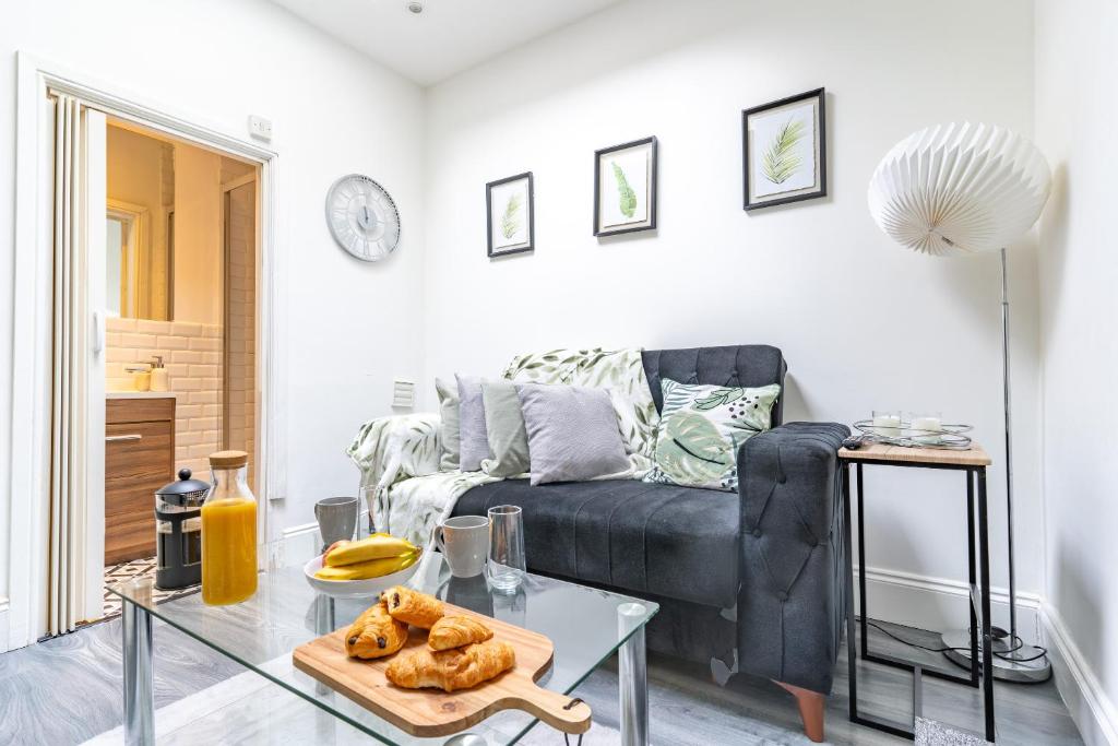 uma sala de estar com um sofá e uma mesa de vidro em Prime Location - Cosy Apartment near Emirates Stadium em Londres