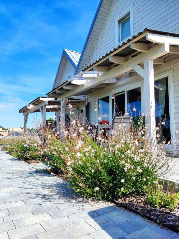 una casa con un porche y flores delante de ella en Baltic Rafa, en Niechorze
