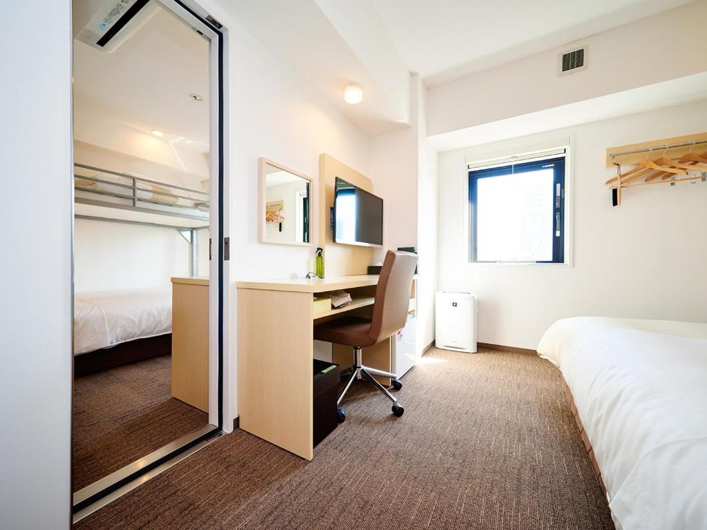 a bedroom with a desk and a bed and a mirror at Super Hotel Akihabara Suehirocho in Tokyo