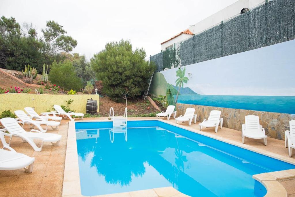 uma piscina com cadeiras brancas e uma piscina em Villa Oasis em Chío
