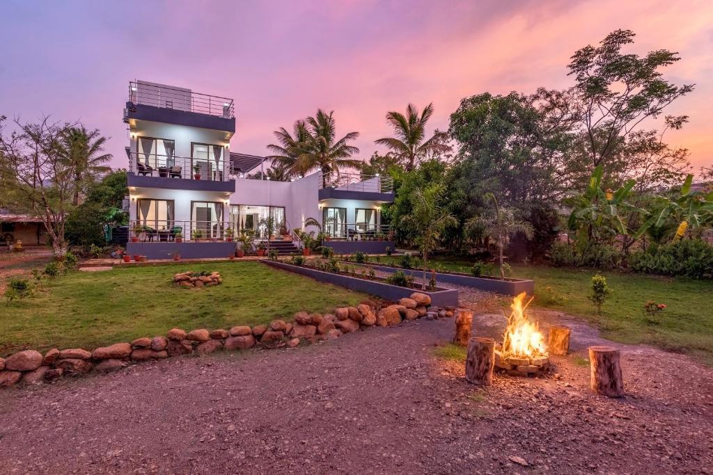una casa con una hoguera delante de ella en SaffronStays Lakeview Nivara - Farm Stay Villa with Private Pool near Pune en Pune