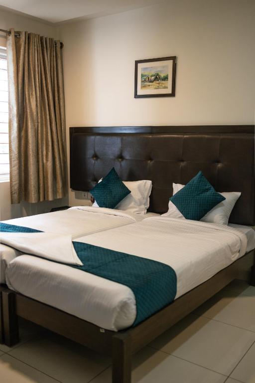 Una cama grande con almohadas verdes y blancas. en Catalyst Suites, Rajaji Nagar, en Bangalore