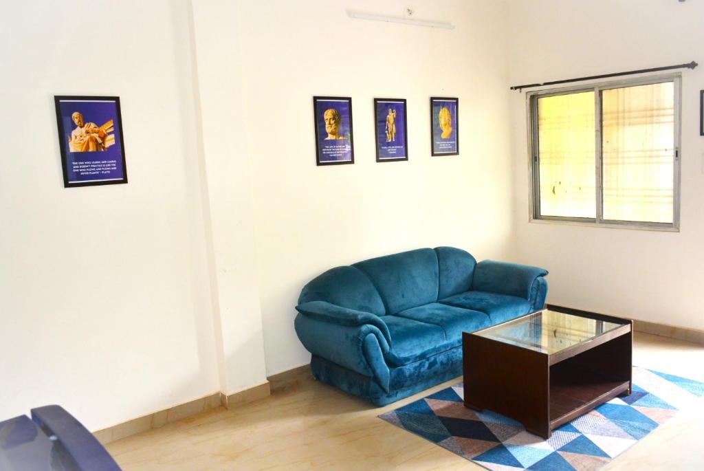 a living room with a blue couch and a table at Blue Beds Homestay, Exotic 2BHK AC House in Jabalpur