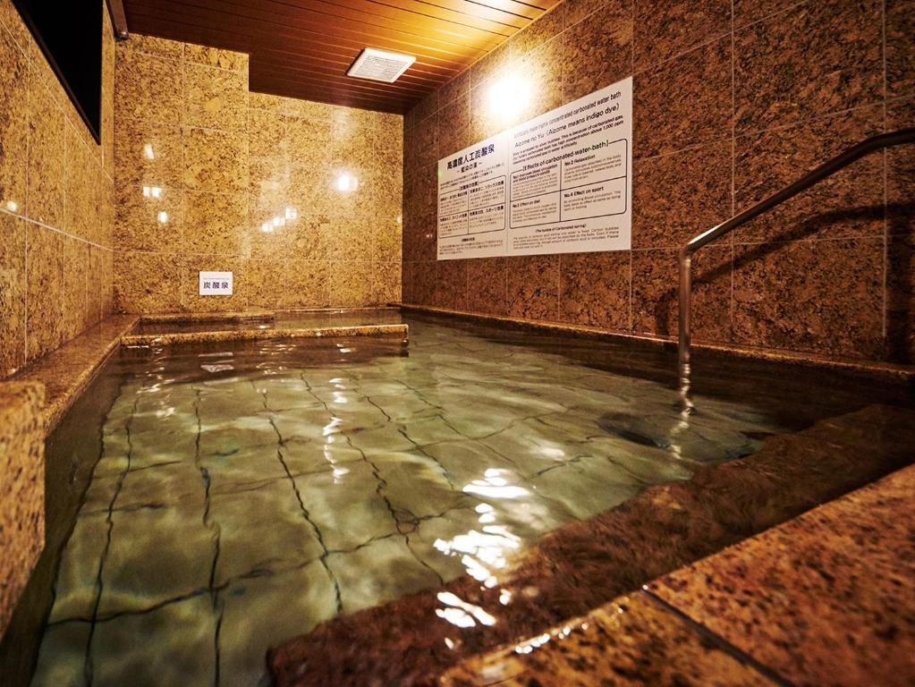 a pool of water in a room with a stone wall at Super Hotel Akihabara Suehirocho in Tokyo