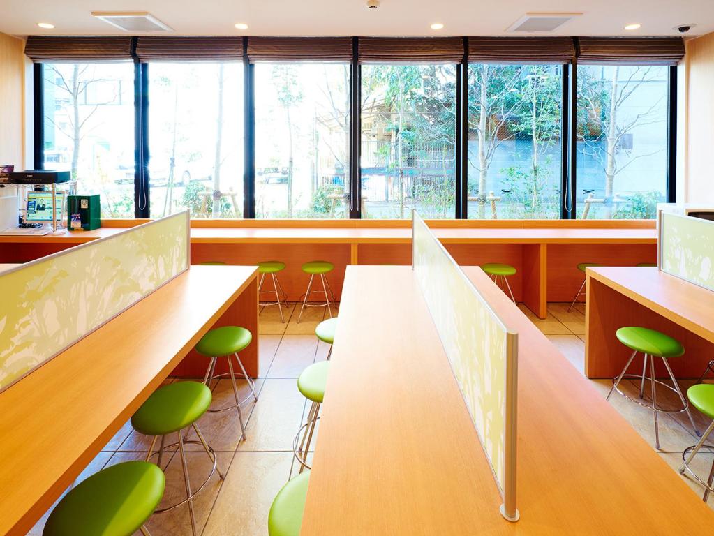 a cafeteria with green stools and tables and windows at Super Hotel Akihabara Suehirocho in Tokyo