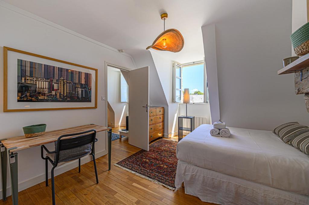 une chambre avec un lit, un bureau et une table dans l'établissement Au coeur des Remparts - Bel appt coeur de Vannes, à Vannes