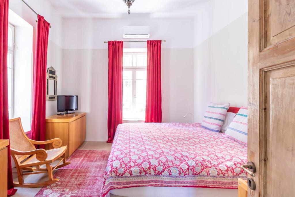 a bedroom with a bed and a window with red curtains at Brand New Gem In Talbiyeh in Jerusalem