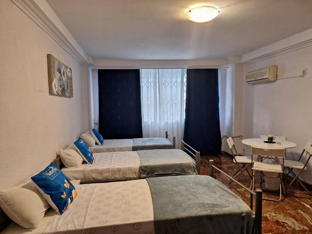 um quarto de hotel com três camas e uma mesa em Pension El Dorado em Alicante