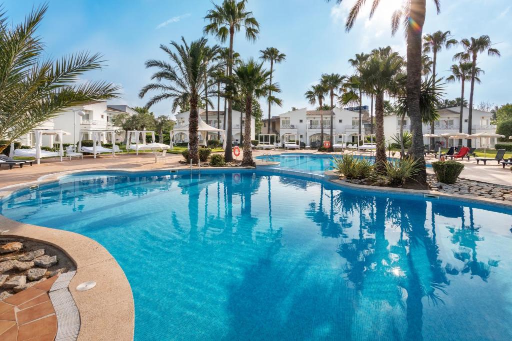 una gran piscina con palmeras en un complejo en Garden Holiday Village - Adults Only, en Playa de Muro