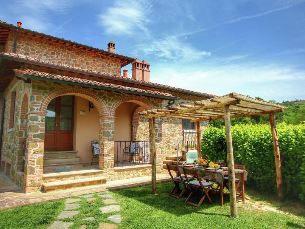 a stone house with a table and a pergola at Luxurious apartment in Lucignano with views in Lucignano