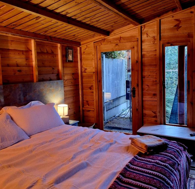 ein Schlafzimmer mit einem Bett in einer Holzhütte in der Unterkunft Cosy Cabin with Free Parking near Central London in Barkingside