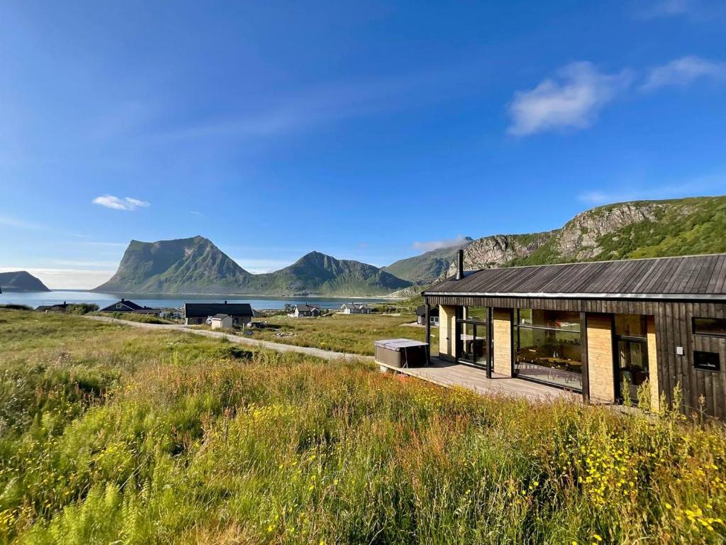 a house in a field with mountains in the background at Atlantic Panorama Lofoten in Leknes