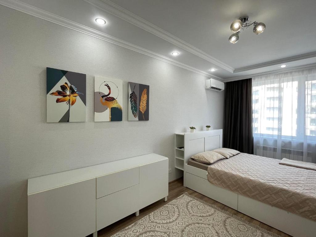 Un dormitorio con una cama y cuadros en la pared. en Nova Center, en Astana