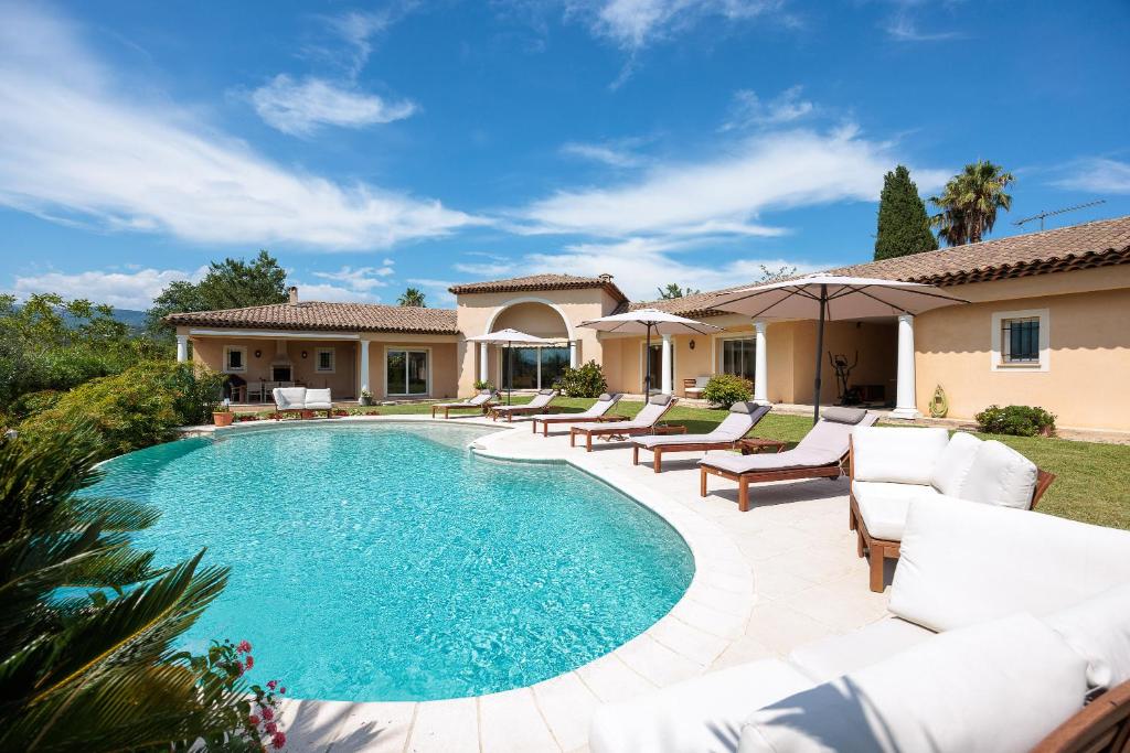 une piscine avec des meubles blancs et une maison dans l'établissement Villa Sole - Recharge and Dream, à Saint-Paul-de-Vence