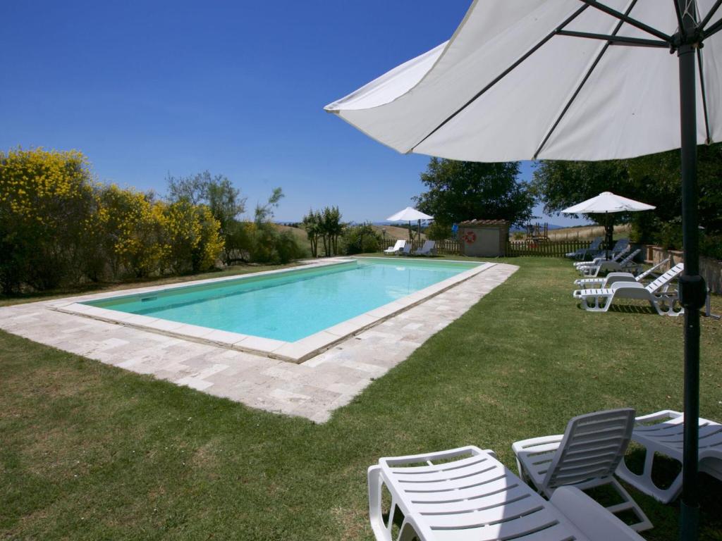 - une piscine avec des chaises longues et un parasol dans l'établissement Lovely farmhouse in Tuscany with panoramic view, à Castelnuovo Berardenga
